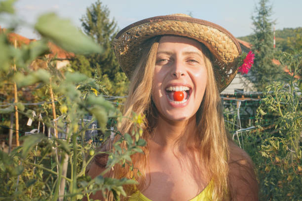 istock woman at farming field biting cherry tomato 1073390882