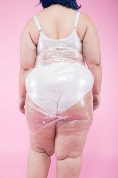 istock plus size model sitting nude behind a desk with a white empty plate on it 1073392526