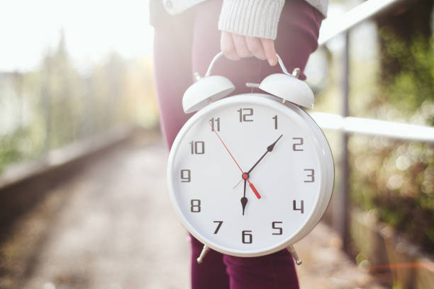 frau hält eine uhr - number alarm clock clock hand old fashioned stock-fotos und bilder