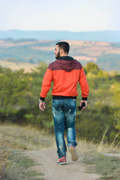 Handsome adult man hiker hiking at beautiful yellow grass mountain meadow.