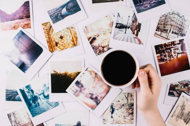 Coffee and Polaroids A hand holding a mug with coffee between a bunch of polaroids printing out photos stock pictures, royalty-free photos & images