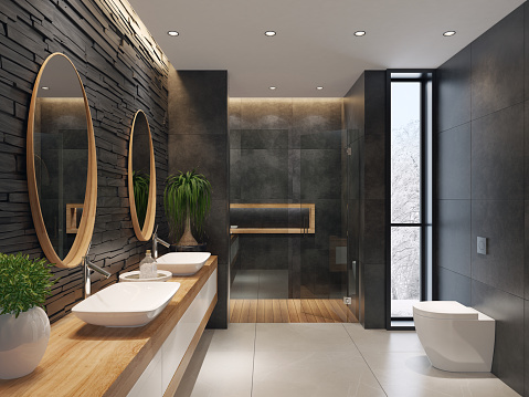 contemporary minimalist bathroom with two round mirrors and wooden frame.
natural stacked black matte stone wall with large black matte tiles.
two rectangular white wash basins are on top of the long wooden cabinet with
white doors. large white matte floor tiles. wooden floor tiles in walk-in shower.
ceiling strip cove lighting with embedded spotlights.