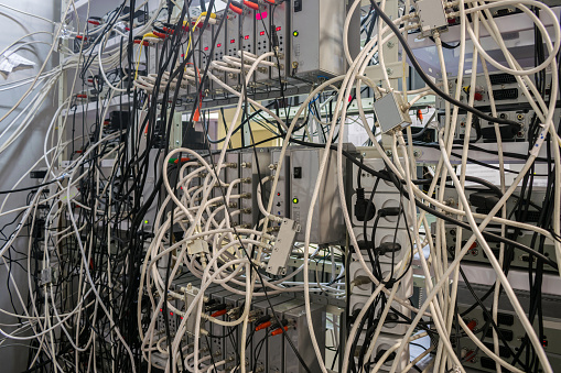 Many TV wires randomly intermingle among themselves in the racks of the server room of the TV station.  Telecommunication equipment of a cable television provider