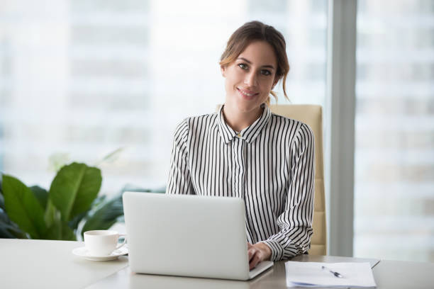 Head shot portrait of confident businesswoman at workplace Head shot portrait of confident businesswoman at workplace, smiling woman employee sitting behind laptop and looking at camera. Staff at work. candidate photos stock pictures, royalty-free photos & images