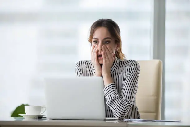 Shocked young woman looking at laptop screen. Frightened businesswoman receiving bad news, deal broke down, notification, bankruptcy, troubled with financial problems or debt.