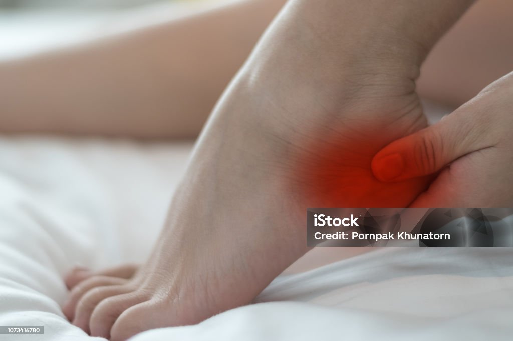 Heel Pain or plantar fasciitis concept. Hand on foot as suffer from inflammation feet problem of Sever's Disease or calcaneal apophysitis. Human Foot Stock Photo