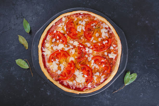 istock pizza Margherita with cheese and tomatoes on a dark background 1073419280