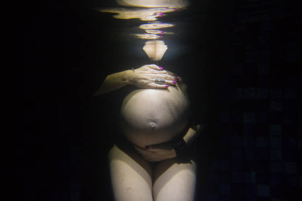 Pregnant Woman A pregnant woman during a swimming pool photo shooting. water birth stock pictures, royalty-free photos & images
