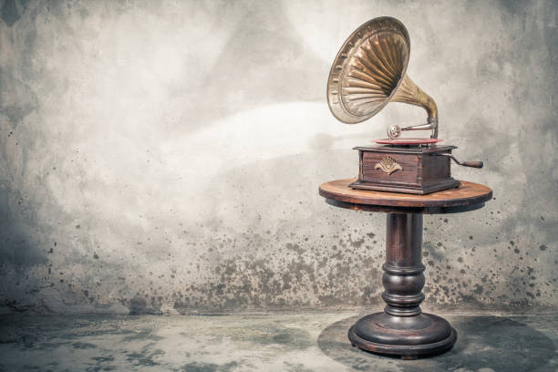 vintage antique gramophone phonograph turntable with brass horn and red color vinyl disc record on wooden table front concrete wall background with shadow. retro old style filtered photo - radio 1930s imagens e fotografias de stock