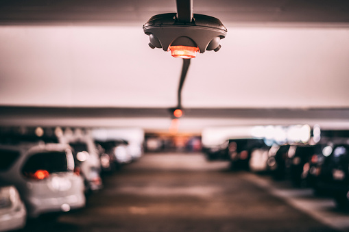 A string of free parking space sensors hanging from a ceiling in a parking garage.