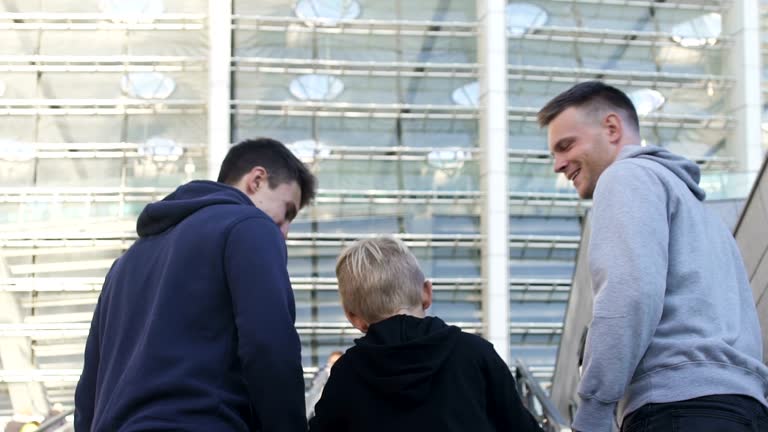 Three brothers running upstairs to stadium, football fans, supporting team