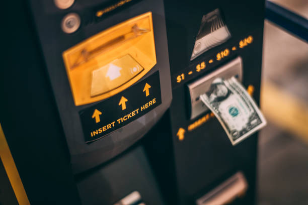 A close-up of a dollar bill inserted into a parking ticket machine in a parking garage