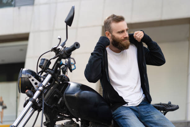 istock Smiling young biker with motorcycle putting on hoodie 1073436240