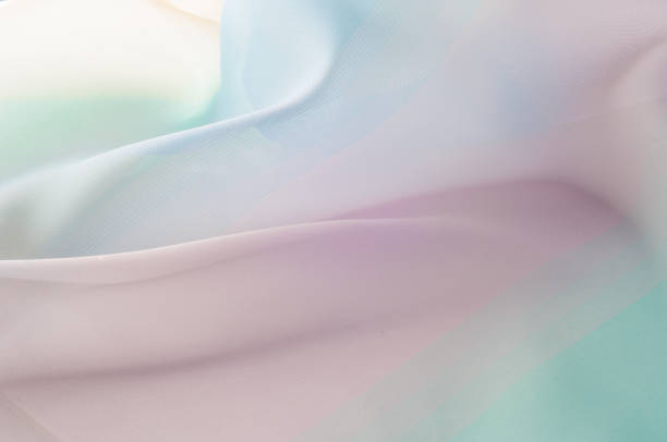 istock Texture, background, pattern. Silk fabric is transparent, yellow-pink green in blue. Abstract soft chiffon texture background. 1073441244