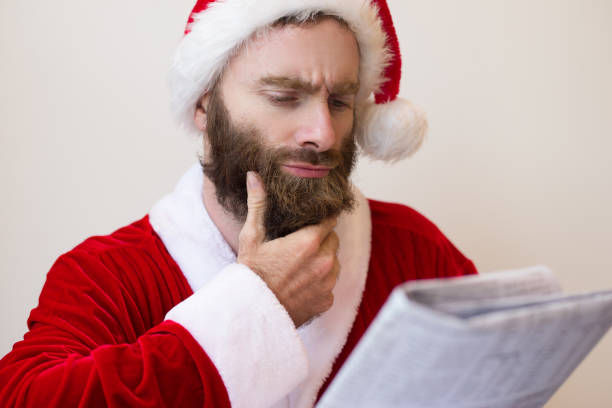 Pensive guy wearing Santa costume and reading newspaper
