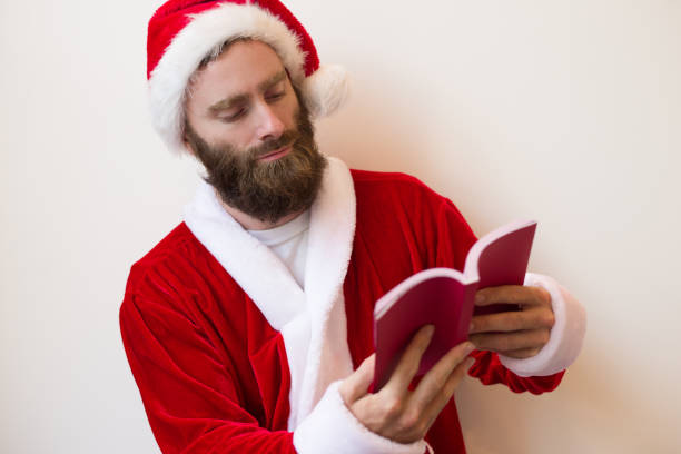 istock Serious guy wearing Santa costume and reading book 1073442840