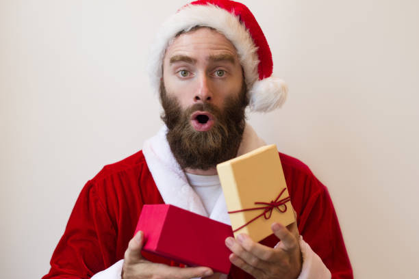 istock Shocked guy wearing Santa costume and opening gift box 1073442882