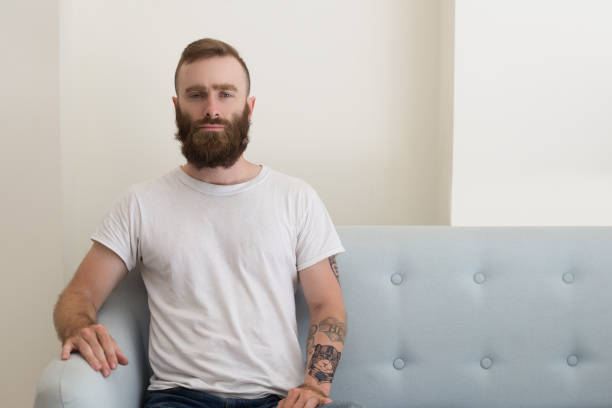 istock Serious brutal hipster man sitting on luxurious sofa confidently 1073442968