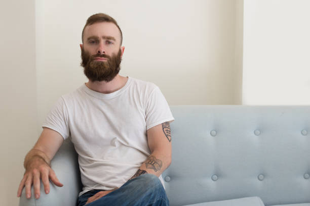 Serious handsome young bearded man with tattoo on arm
