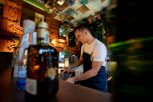 istock Latin american handsome waiter working behind bar counter at a restaurant smiling 1073455412