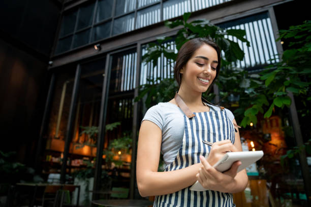 istock Young latin american cheerful waitress writing down something on notepad at the restaurant 1073455568