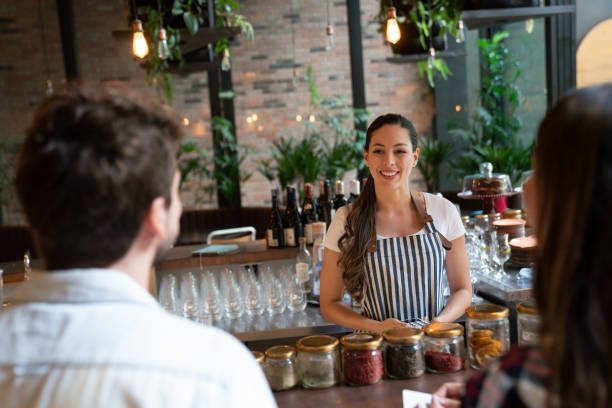 istock Latin american friendly waitress holding an eftpos while talking to unrecognizable customer couple ready to pay at a restaurant 1073456968