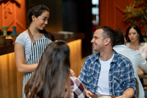 istock Young latin american waitress taking order from man on a date looking very happy 1073458286