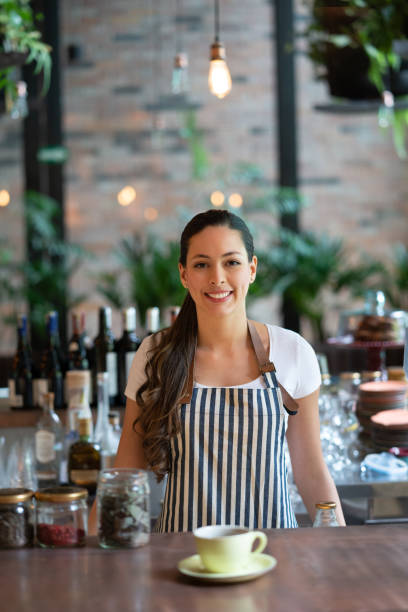 istock Beautiful waitress facing camera smiling while standing behind the bar counter 1073458336