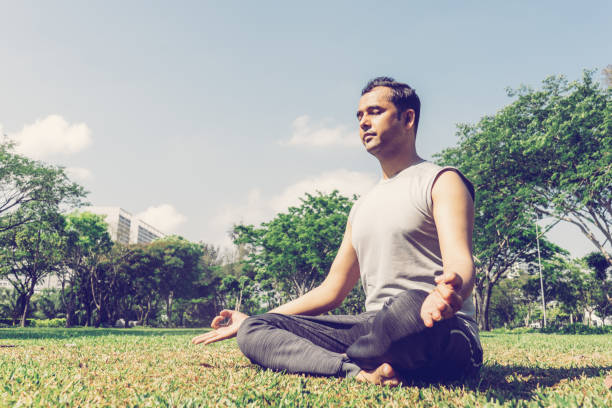 istock Indian man meditating in lotus pose outdoors on summer lawn 1073460952