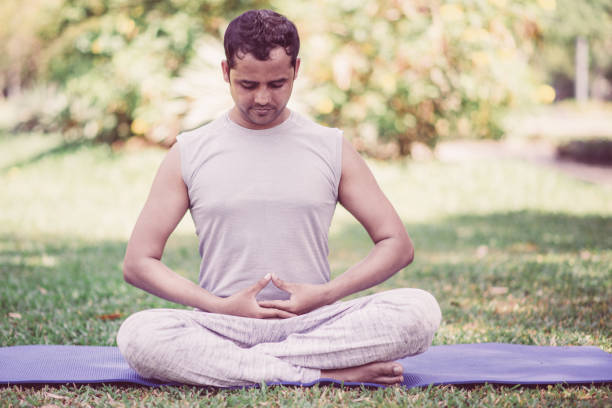 istock Focused Indian guy doing yoga asanas in park 1073460972