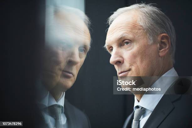 Closeup Of Serious Pensive Grayhaired Mature Politician With Wrinkled Forehead Looking Out Window Reflection Effect Stock Photo - Download Image Now