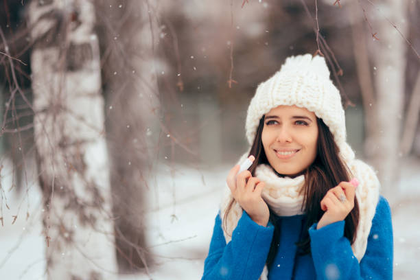 istock Happy Woman Applying Lip Balm Outdoors in Winter 1073484036