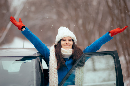 Smiling girl next to her vehicle relaxing in winter journey trip