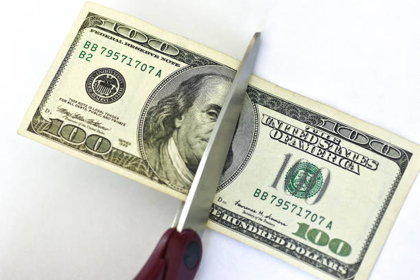 istock Scissors cut hundred dollar bill on white background 1073492860