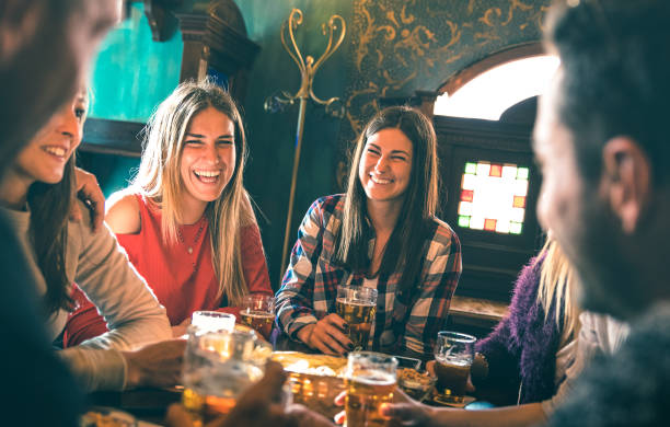 group of happy friends drinking beer at brewery bar restaurant - friendship concept with young millenial people enjoying time together having fun vintage pub - focus right woman - high iso image - beer pub women pint glass imagens e fotografias de stock