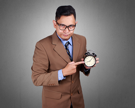 Young Asian businessman wearing suit showing time, serious expression. Close up body portrait