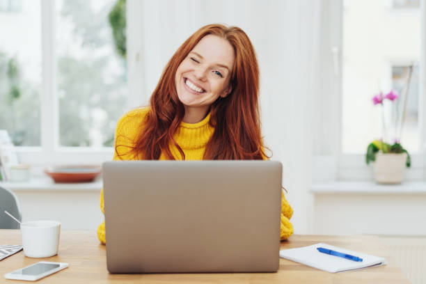 joven mujer pelirroja feliz usando laptop - parpadear fotografías e imágenes de stock