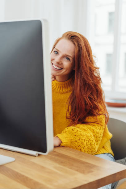 istock pretty young redhead woman working at a desktop 1073554098