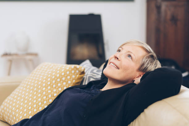 istock Mature smiling woman relaxing on sofa at home 1073558568