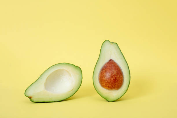 istock Two slices of avocado isolated on yellow background 1073567802