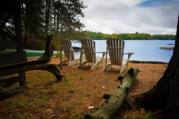 istock White Muskoka chairs on a cottage sandy beach 1073568396