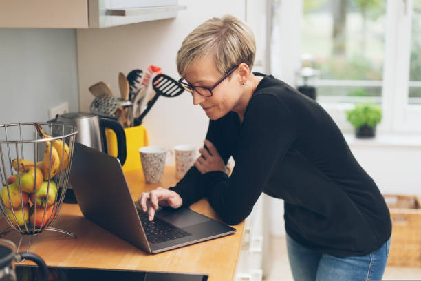 istock Attractive woman using a laptop in a kitchen 1073572512