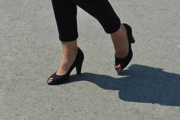 istock Woman's legs with red nails polished in black sandals 1073583758