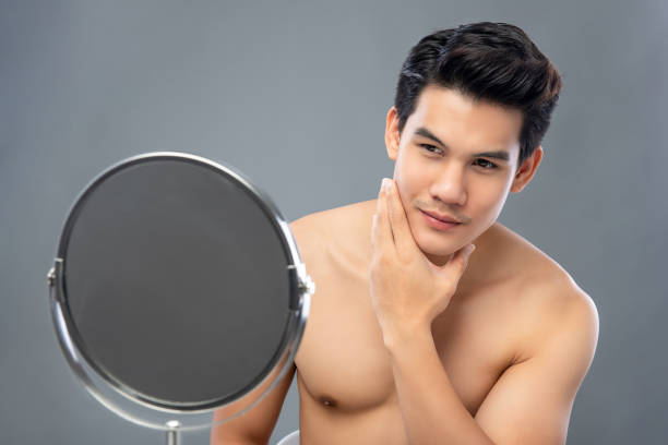自信を持って、鏡で自分自身を見ているアジアの男性モデル - shirtless men male teenager ストックフォトと画像