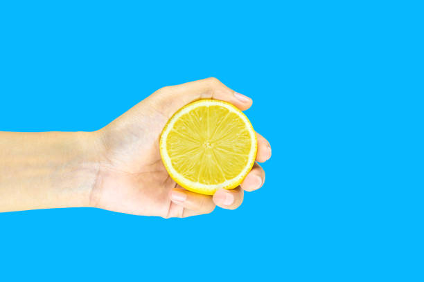 istock woman Hand holding a Half fresh Lemon isolated on blue background 1073594228