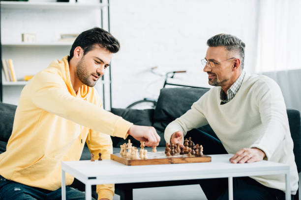istock son and smiling mature father playing chess on weekend at home 1073596264