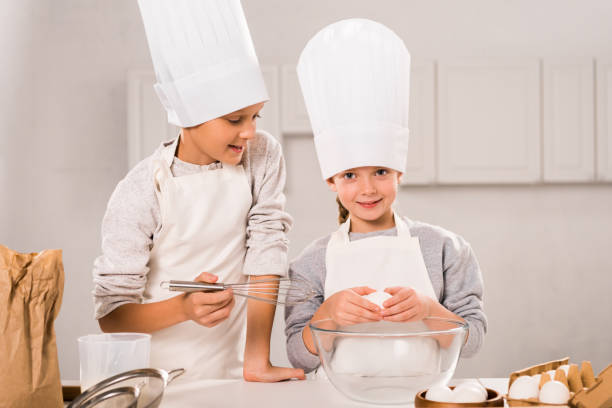istock little children in aprons and chef hats preparing at table in kitchen 1073605180