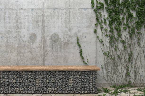 Background with a gray concrete wall with ivy and a bench of stones. Front view with copy space.