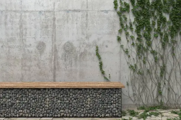 Photo of Background with a gray concrete wall with ivy and a bench of stones. Front view with copy space.