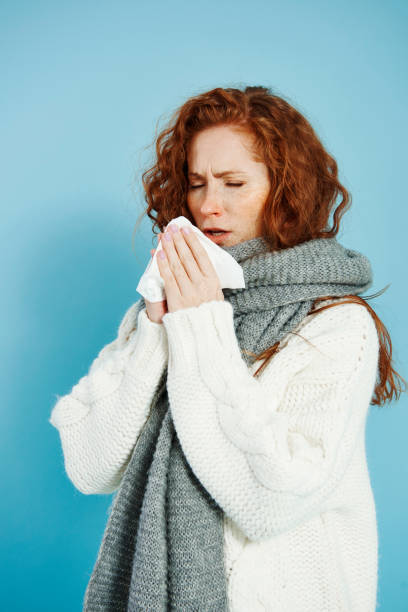 istock Sick girl sneezing and wiping her nose 1073609414